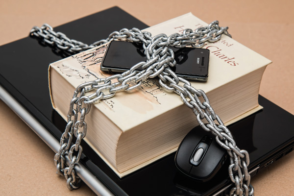 Chain around book, phone and laptop