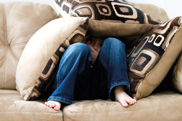 Child on sofa hiding under cushions