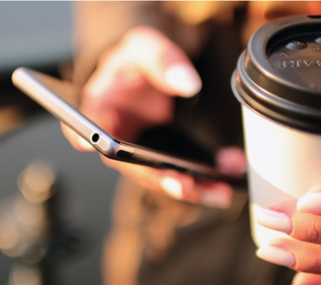 Lady on mobile phone holding a takeaway cup of coffee