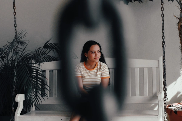 Lady sitting on bench seen through eye of a chain