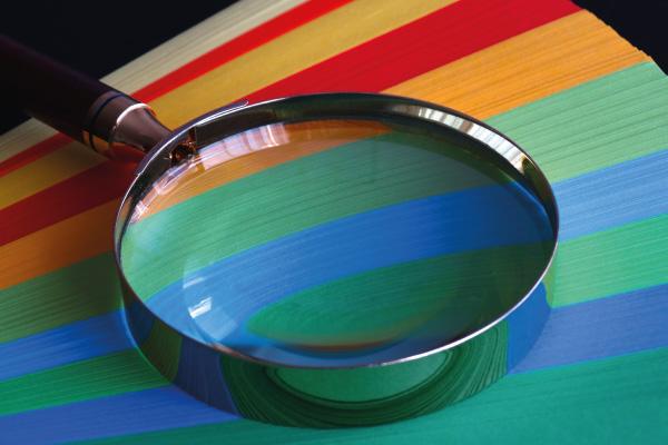 Magnifying glass resting on the end of coloured paper