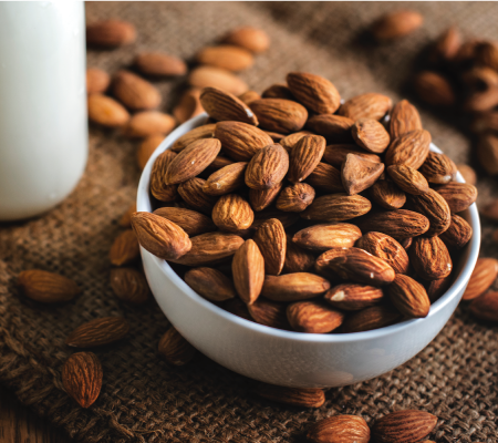 Nuts in a bowl next to a jar of milk