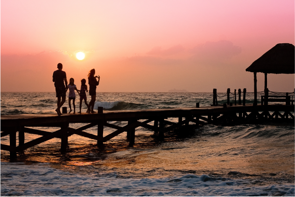 Wood pier into sea with family watching the sunset