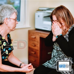 Lady providing first aid for mental health support to an upset colleague
